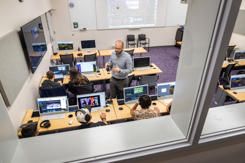 Teacher discussing with students in a computer classroom